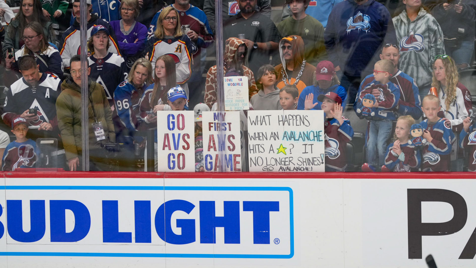 mans holding up signs cheering through glass at ice hockey game during warm up